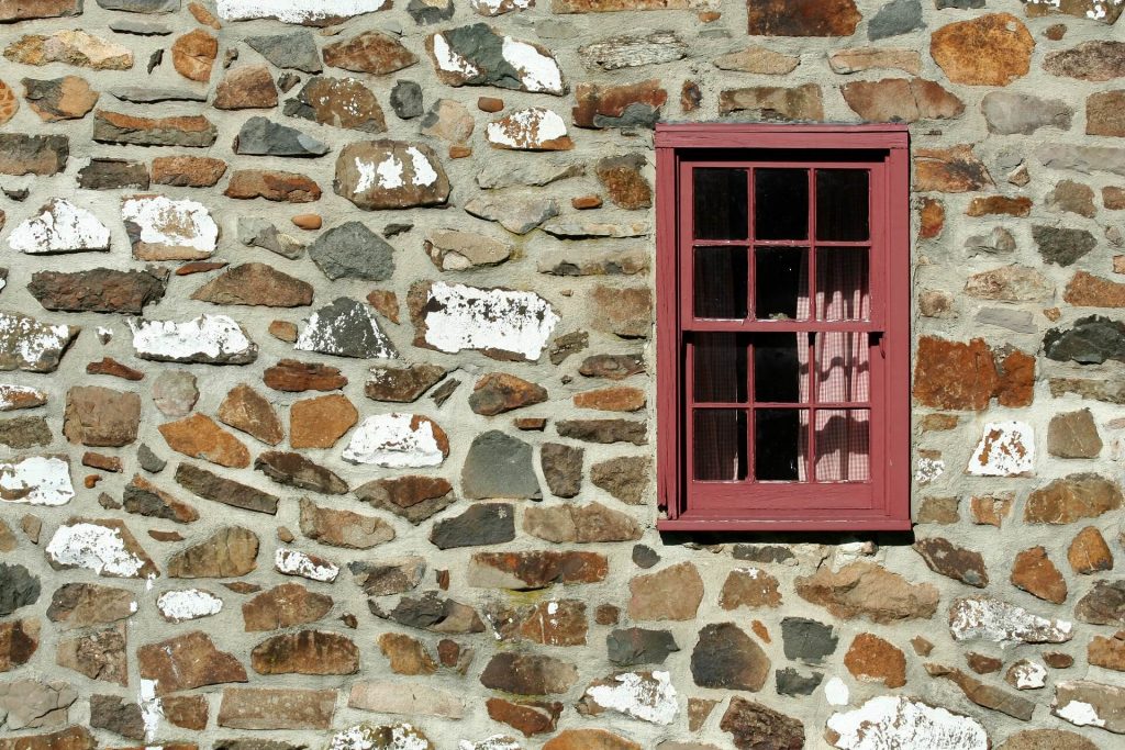 En stenvägg med ett rött fönster